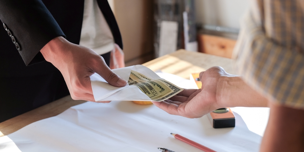 Close up two hands while paying spot bonus to worker and employee