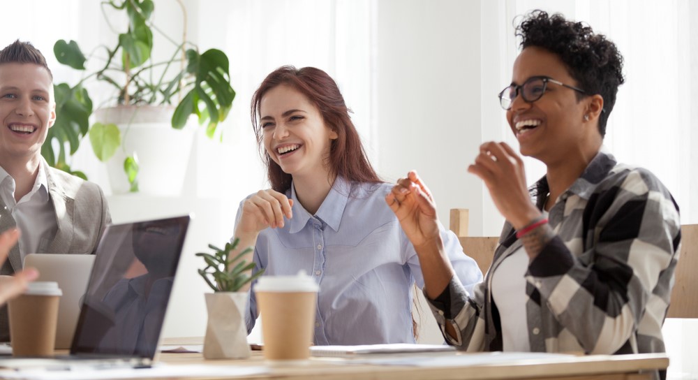 Happy joyful business people laughing at funny joke talking at work break